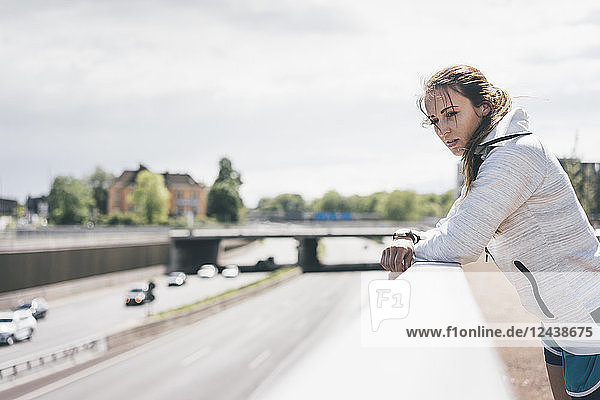 Sportive young woman leaning on railing at motorway