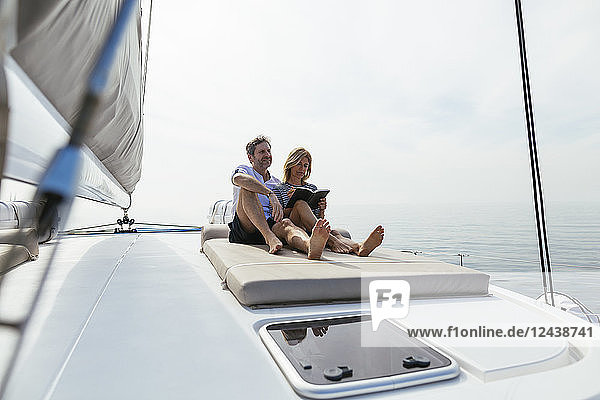 Couple sitting on deck of catamaran  relaxing  woman reading book