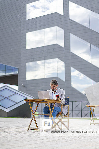 Spain  Barcelona  businessman working on laptop outdoors