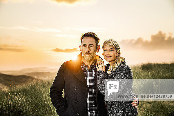 Couple standing in dunes at sunset