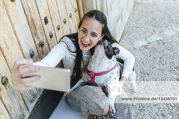 Young woman using smartphone  taking a selfie with her dog