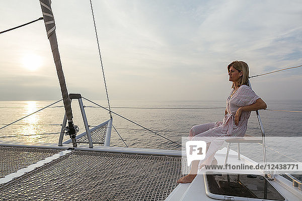 Mature woman on catamaran  watching sunset