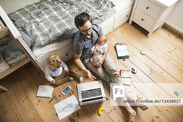 Father with his little son and baby daughter working from home