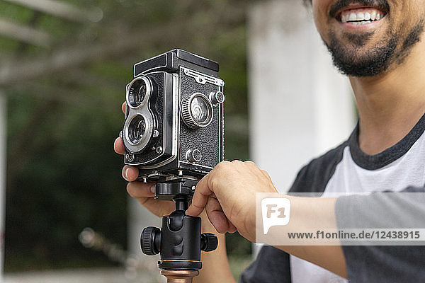 Close-up of happy young man using vintage camera