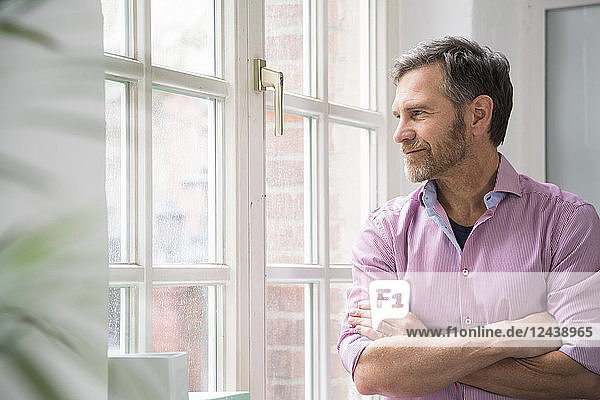 Portrait of a man looking out of window in office