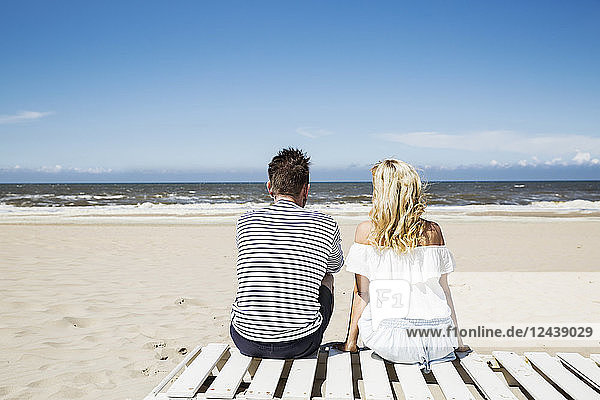 Couple sitting on boardwalk on the beach