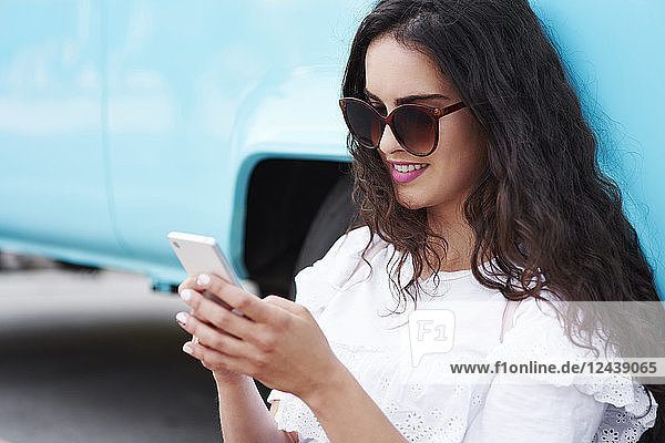 Smiling young woman using cell phone outdoors