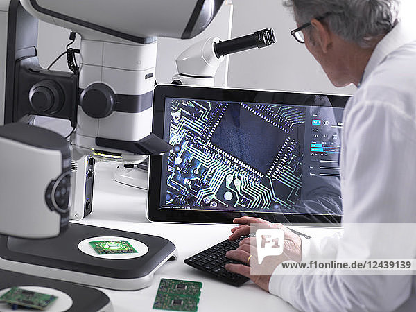 Engineer using a 3d stereo microscope for quality control in the manufacturing of circuit boards for the electronics industry