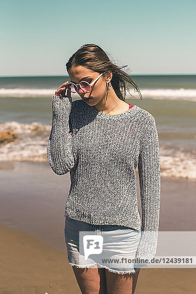 Spain  young woman wearing sunglasses standing on the beach