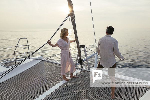 Mature couple standing on catamaran trampoline  enjoying their sailing trip