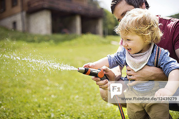 Little boy with his father watering the lawn