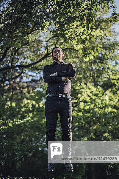 Young businessman levitating in park