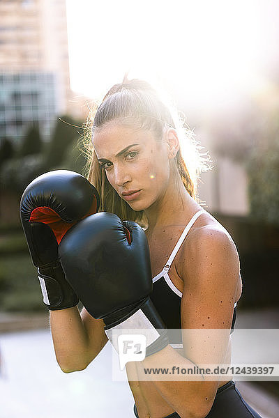 Portrait of sportive young woman boxing in the city