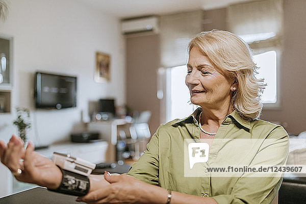 Smiling senior woman taking her blood pressure