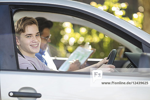 Portrait of smiling learner driver with instructor in car