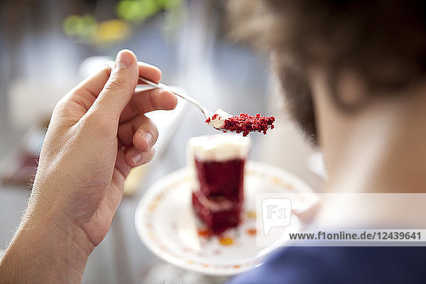 Young man eating fancy cake  close-up