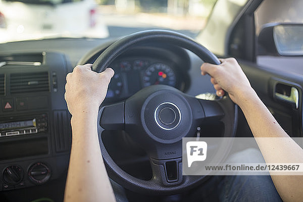 Male hands in car holding steering wheel