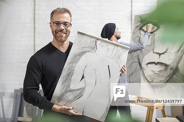 Smiling man holding drawing in artist's studio