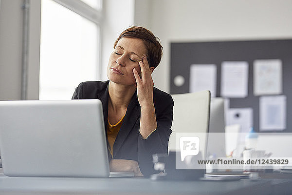 Businesswoman sitting in office  having a headache