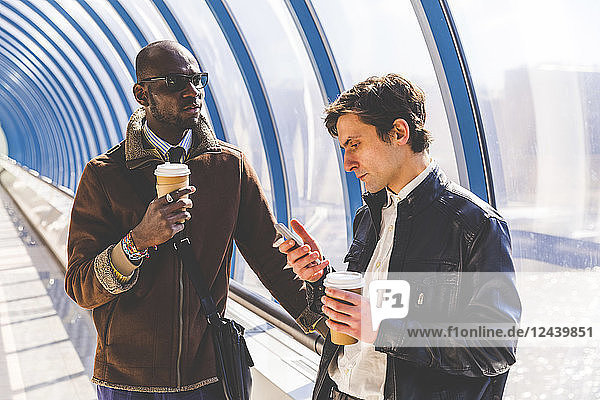 Two businessmen with coffee to go and smartphone