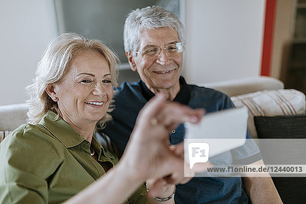 Senior couple at home sitting on couch taking a selfie