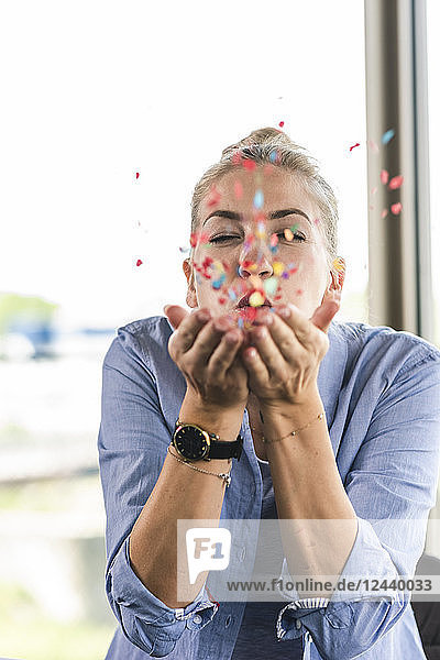 Happy businesswoman blowing confetti  celebrating success