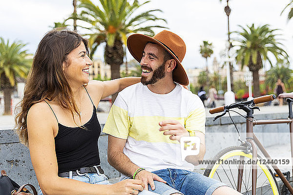 Spain  Barcelona  couple sitting on bench having fun together