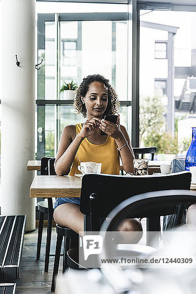 Young woman sitting in cafe  drinking coffee  reading text messages