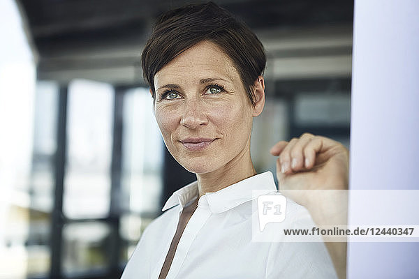 Portrait of smiling businesswoman in office looking out of window