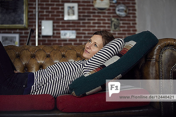 Woman on sofa relaxing at home  daydreaming