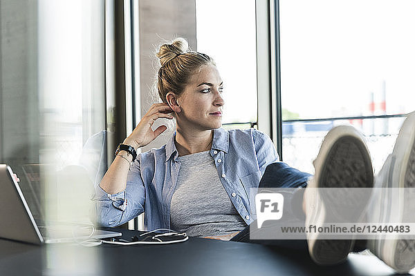 Young businesswoman sitting at desk with feet up  taking a break