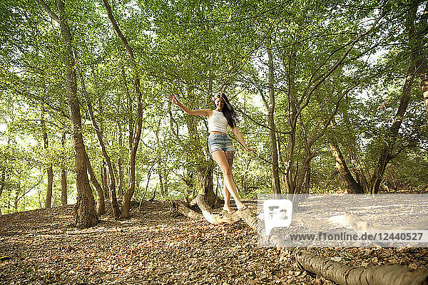Young woman in forest balancing on a log