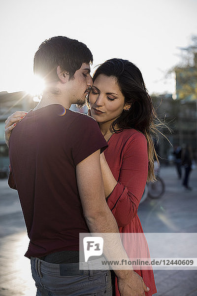 Affectionate young couple standing on city square at sunset