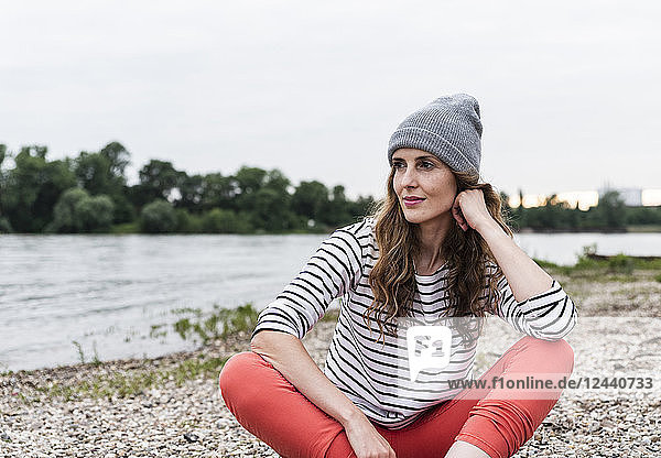 Portrait of woman wearing wooly hat sitting at the riverside