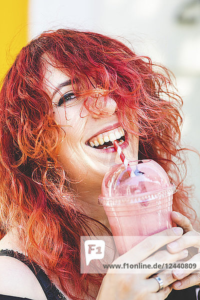 Portrait of laughing woman drinking smoothie