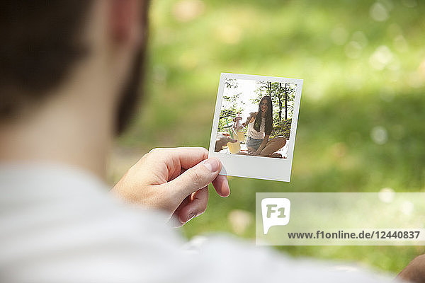 Man holding instant photo of his girlfriend  partial view