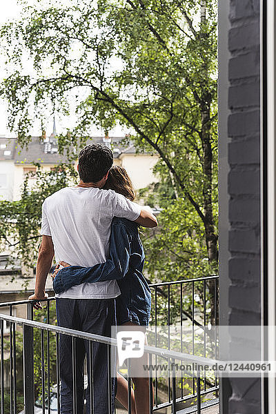 Rear view of couple in nightwear standing on balcony hugging