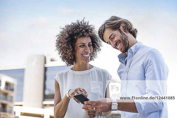 Businessman and woman having a meeting outdoors  using smartphone
