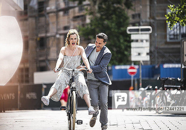 Happy carefree couple with bicycle in the city