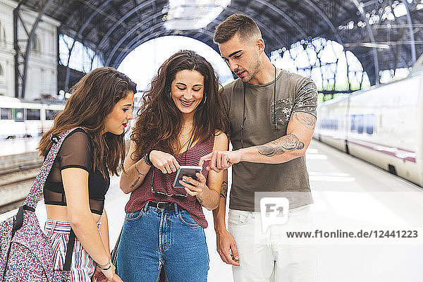 Friends with cell phone on train station platform
