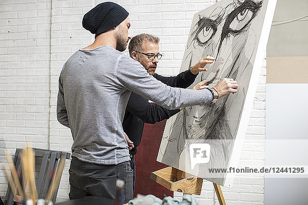 Artist discussing drawing with man in studio