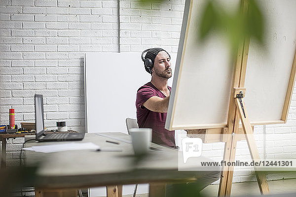 Artist wearing headphones drawing in studio