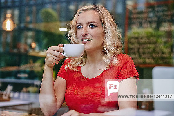 Portrait of smiling blond woman drinking coffee in a cafe