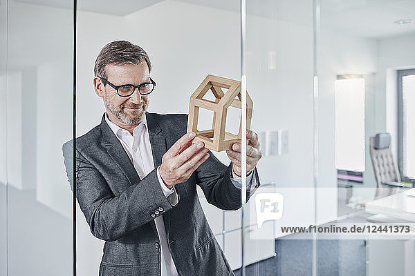 Smiling businessman looking at architectural model in office
