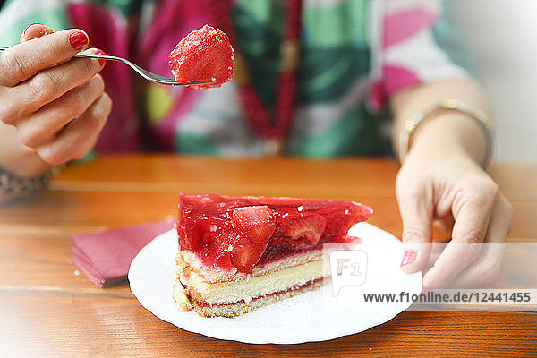 Close-up of woman eating strawberry cake in street cafe