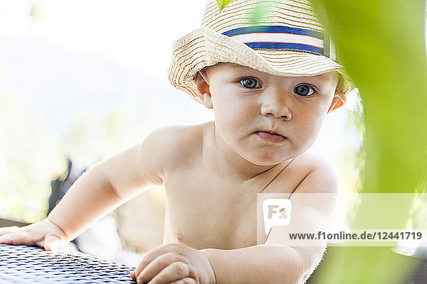Portrait of curious baby boy wearing straw hat