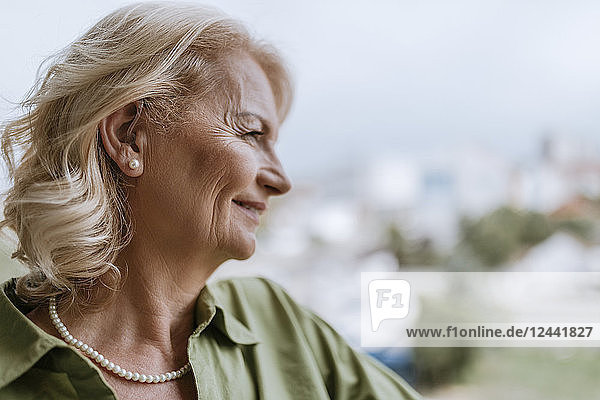 Smiling senior woman with hearing aid outdoors