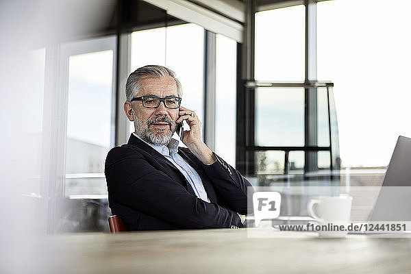 Businessman on cell pohone at desk in office