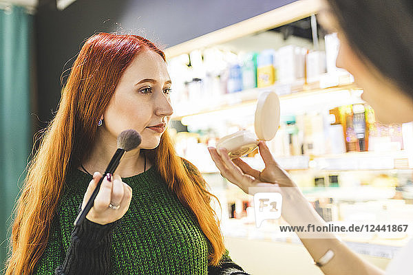 Two women in a cosmetics shop trying make up