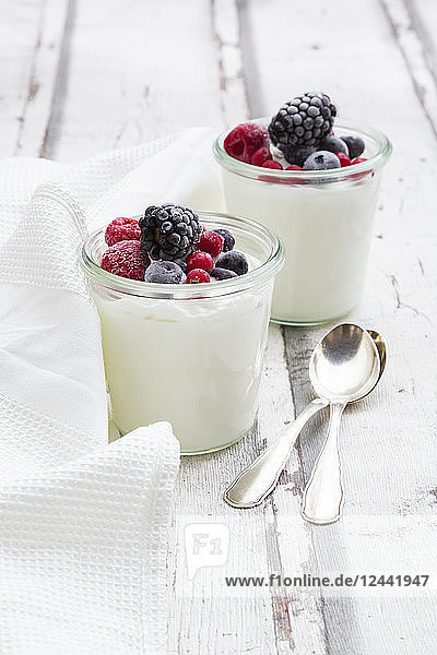 Two glasses of Greek yogurt with frozen berries